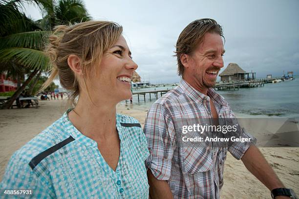 man and woman smiling walking on beach. - hair back stock pictures, royalty-free photos & images