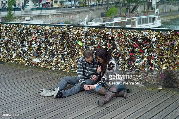 Couple take pictures of the Love Padlocks on the Le Pont Des Arts bridge on May 7, 2014 in Paris, France. In recent years Le Pont Des Arts has...