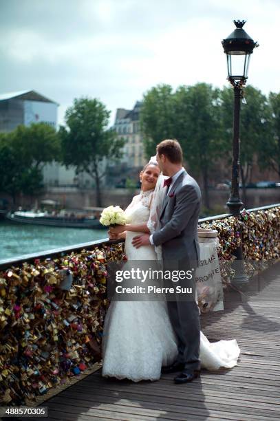 Newlywed couple pose for pictures in front of the Love Padlocks on the Le Pont Des Arts bridge on May 7, 2014 in Paris, France. In recent years Le...