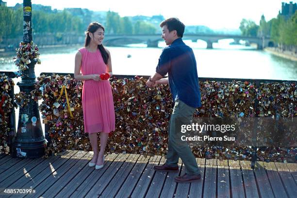 Couple pose in front of the Love Padlocks on the Le Pont Des Arts bridge on May 7, 2014 in Paris, France. In recent years Le Pont Des Arts has...