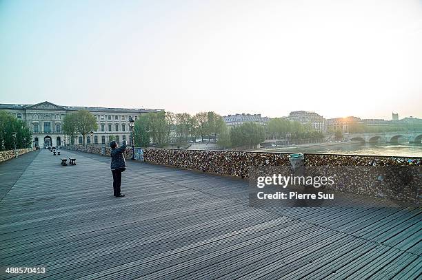 Tourist takes a picture of the Love Padlocks on the Le Pont Des Arts bridge on May 7, 2014 in Paris, France. In recent years Le Pont Des Arts has...