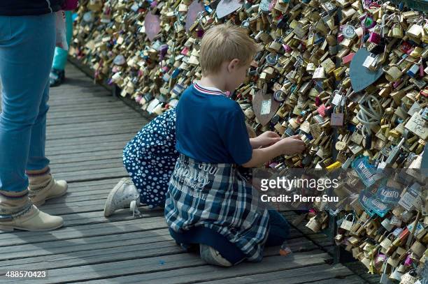 Kids attaching Love Padlocks on the Le Pont Des Arts bridge on May 7, 2014 in Paris, France. In recent years Le Pont Des Arts has attracted tourists...