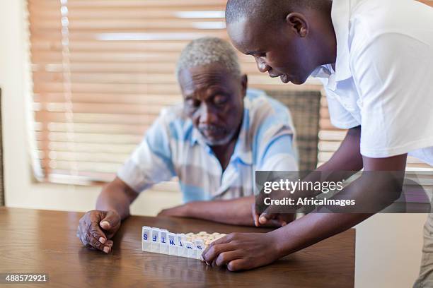 afrikanischer enkel gibt seinem großvater medikamente. - great depression stock-fotos und bilder