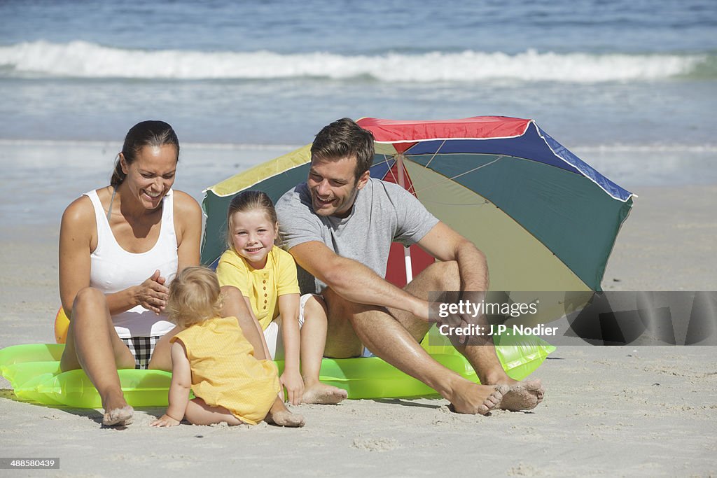 Young family with 2 children sitting on beach