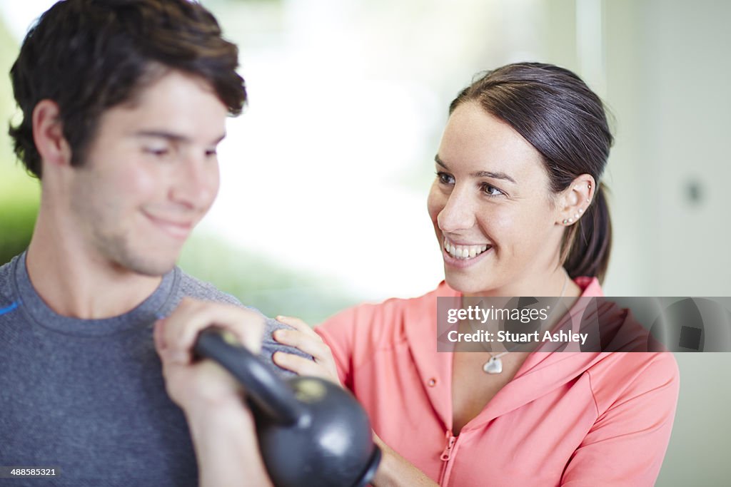 Personal trainer helping male exercise