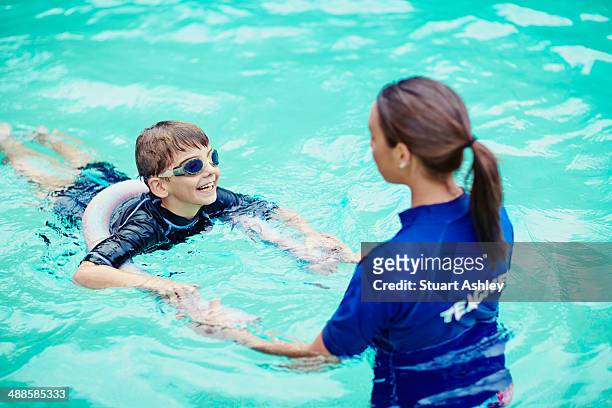 young boy learning to swim in pool with teacher - leren zwemmen stockfoto's en -beelden