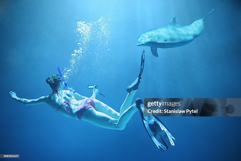 Girl filming dolphin underwater