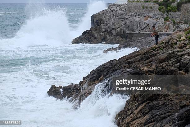 Man fishes as big waves hit the coast of Comillas in the northern Spanish region of Cantabria, on September 16, 2015. AFP PHOTO / CESAR MANSO