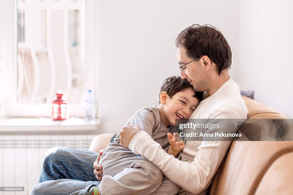 Father and son cuddling on a coach