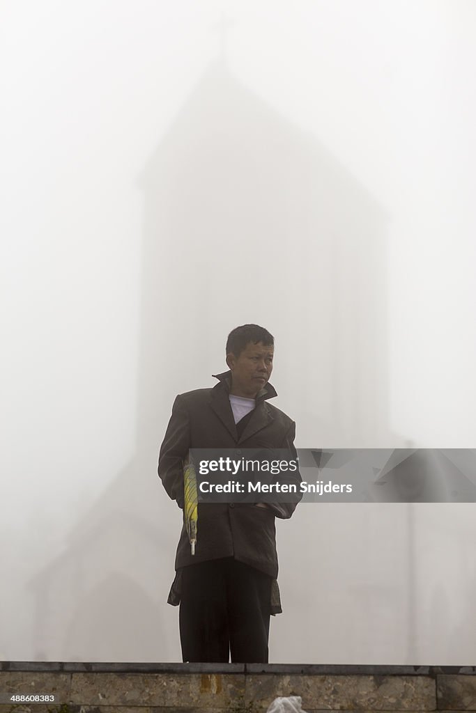 Man with umbrella at misty church