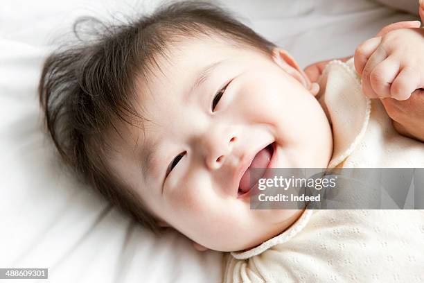 baby boy smiling on bed - 日本人　赤ちゃん ストックフォトと画像