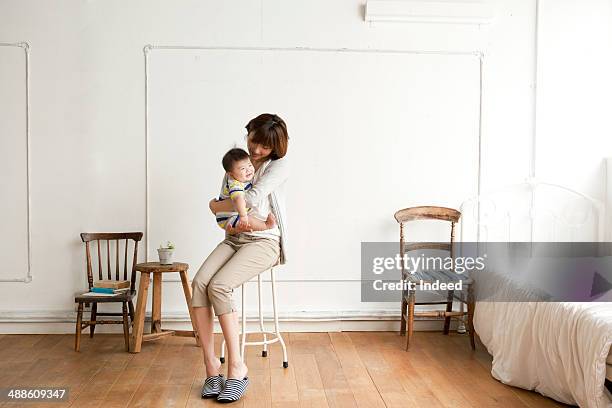 mother holding baby on chair - mum sitting down with baby stockfoto's en -beelden