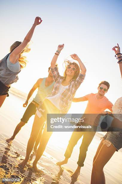 friends dancing on beach in sunset - sunset beach party stock pictures, royalty-free photos & images