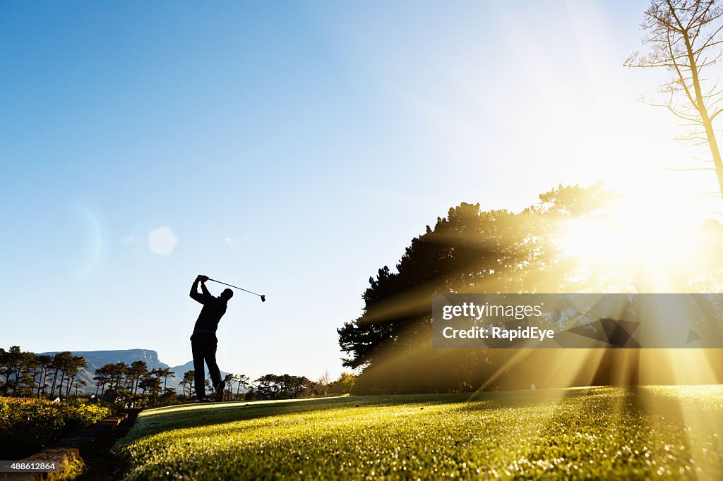 Silhouette der junge golfer Schaukeln auf wunderschönen, sonnendurchfluteten Golfplatz