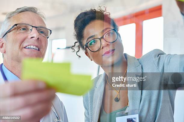 senior doctor and businesswoman brainstorming - medical protective suit stock pictures, royalty-free photos & images
