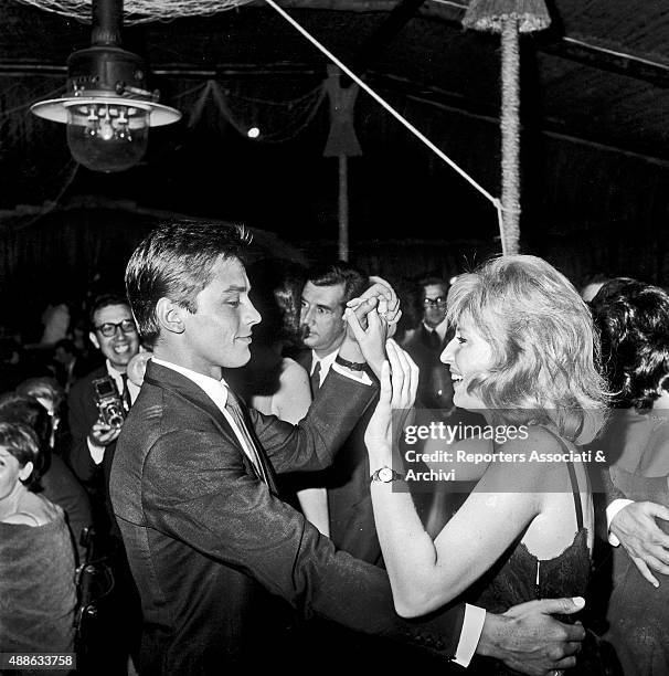 French actor Alain Delon dancing surrounded by other guests and photographers with Italian actress Monica Vitti in a club in Torvaianica, on the...