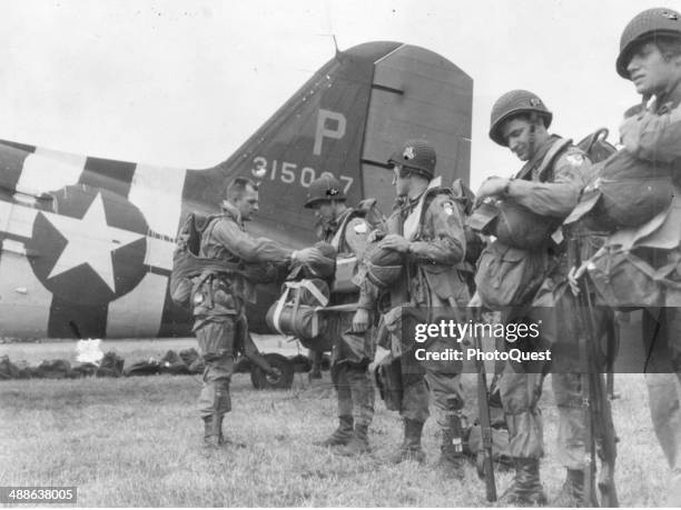 Last-minute check of equipment is made just before American paratroopers leave their English base for an airborne assault on Nazi defenses on the...