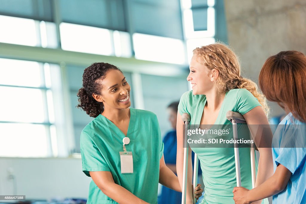 Physical therapist helping teenage patient in rehabilitation hospital