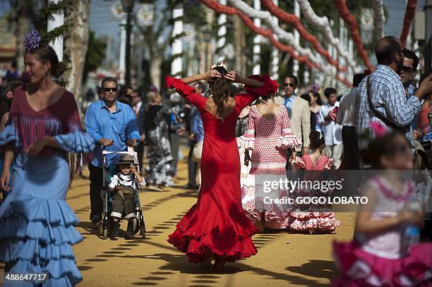 Women wearing traditional Andalusian dresses walk at the Sevilla Fair on April 7, 2014. The fair dates back to 1847 when it was originally organized...