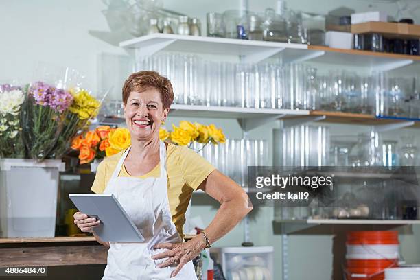 mature woman working in flower shop using digital tablet - kali rose stock pictures, royalty-free photos & images