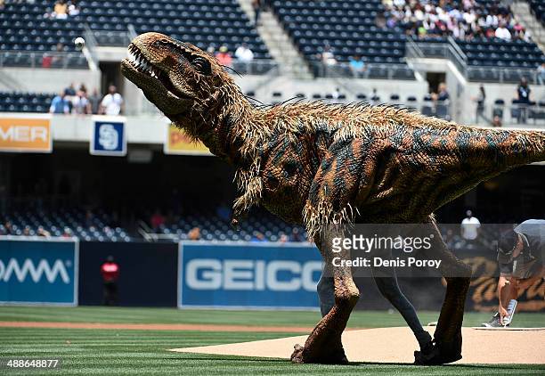 Costumed dinosaur, Baby T, from "Walking with Dinosaurs" throws out the first pitch before a baseball game between the Kansas City Royals and the San...