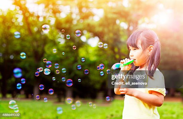 little girl blowing soap bubbles - child bubble stock pictures, royalty-free photos & images