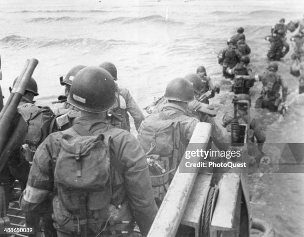 American soldiers with full equipment leap into the surf from a landing craft and wade toward Utah Beach, France, June 6, 1944.