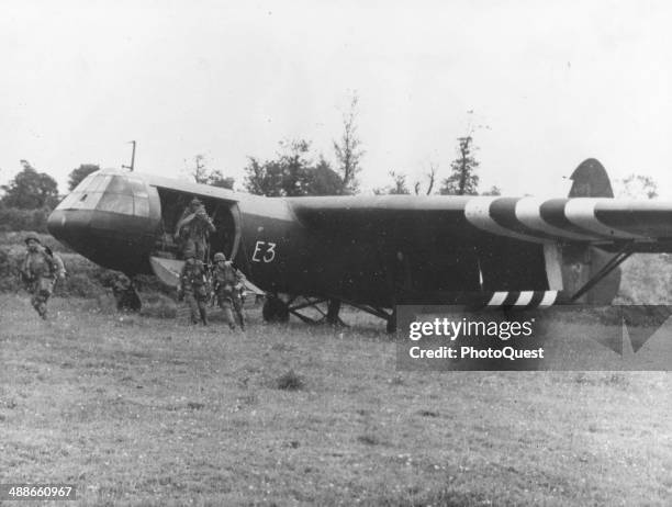 American airborne infantry leap from a glider as they land in a field on a Franch farm to reinforce forward positions in Normandy, during the Allied...