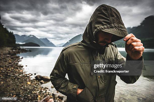 solitude uomo pensoso sul lato lago - parka cappotto invernale foto e immagini stock