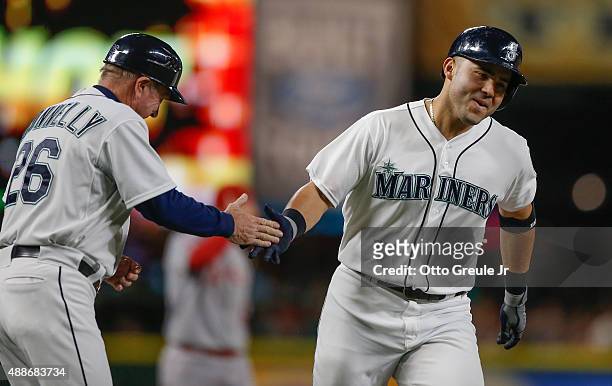 Jesus Montero of the Seattle Mariners is congratulated by third base coach Rich Donnelly after hitting a three-run home run against the Los Angeles...