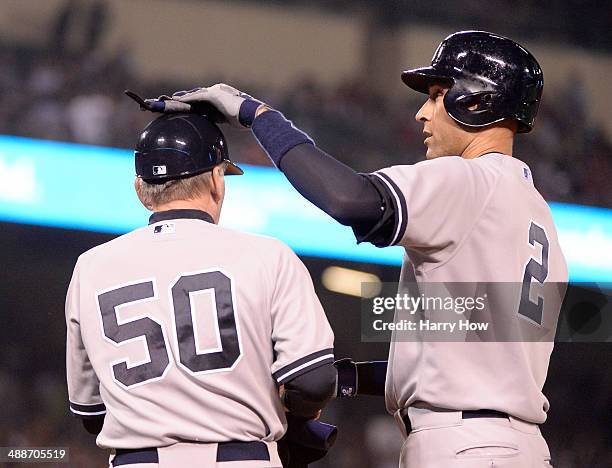 Derek Jeter of the New York Yankees celebrates his single with first base coach Mick Kelleher during the fourth inning against the Los Angeles Angels...