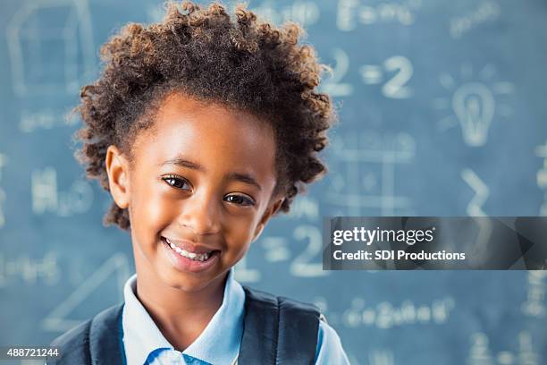 african american elementary schoolgirl in front of blackboard - african american school uniform stock pictures, royalty-free photos & images