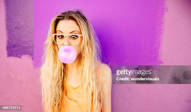 young woman blowing a pink bubble gum - bubble gum stockfoto's en -beelden