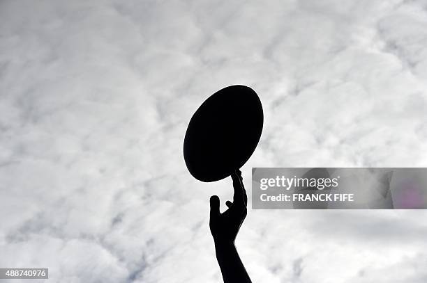 Picture taken on September 17, 2015 shows the silhouette of a detail of a statue of a rugby player reaching for a ball outside Twickenham Stadium,...