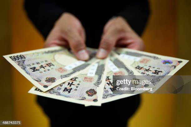 An attendant holds Japanese 5,000 yen banknotes, which have holograms larger than the current design and with a new texture, for a photograph...