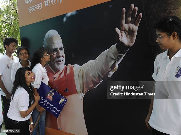 School children pose with the poster put up to celebrate the 65th birthday of Narendra Modi at FICCI Auditorium on September 17, 2015 in New Delhi,...