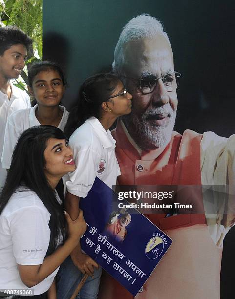 School children pose with the poster put up to celebrate the 65th birthday of Narendra Modi at FICCI Auditorium on September 17, 2015 in New Delhi,...