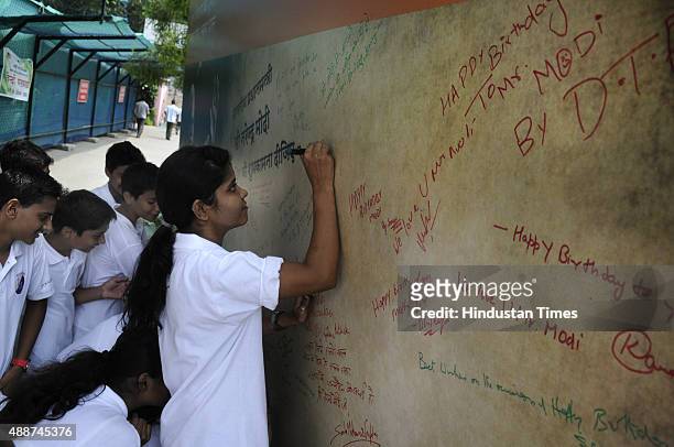 School children writing the messages on the poster put up to celebrate the 65th birthday of Narendra Modi at FICCI Auditorium on September 17, 2015...