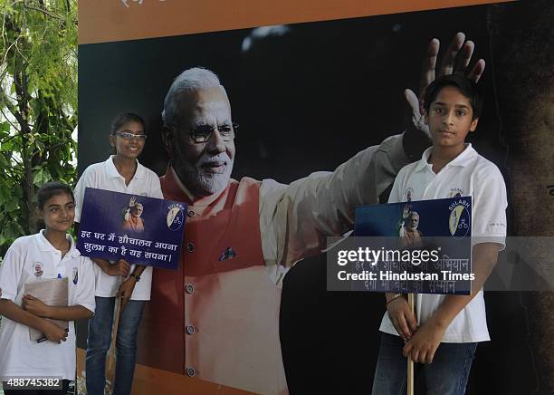 School children pose with the poster put up to celebrate the 65th birthday of Narendra Modi at FICCI Auditorium on September 17, 2015 in New Delhi,...