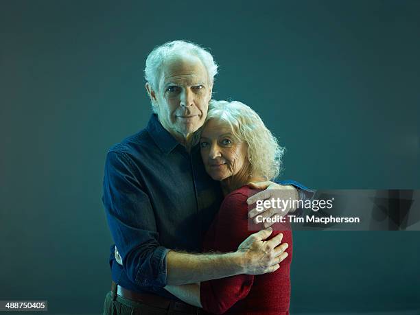 senior man and woman embrace - senioren koppel studio stockfoto's en -beelden