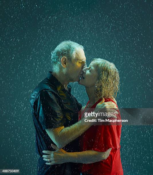 senior couple kissing in the rain - couples kissing shower photos et images de collection