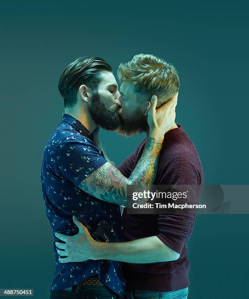 two bearded men kissing - gay person color background stock pictures, royalty-free photos & images