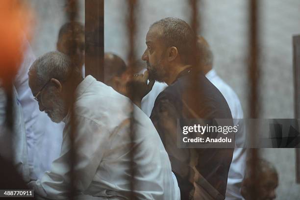 Muslim Brotherhood Leader Mohamed Badie and senior leader of the Muslim Brotherhood Mohamed Beltagy stand inside a defendant's cage during their...