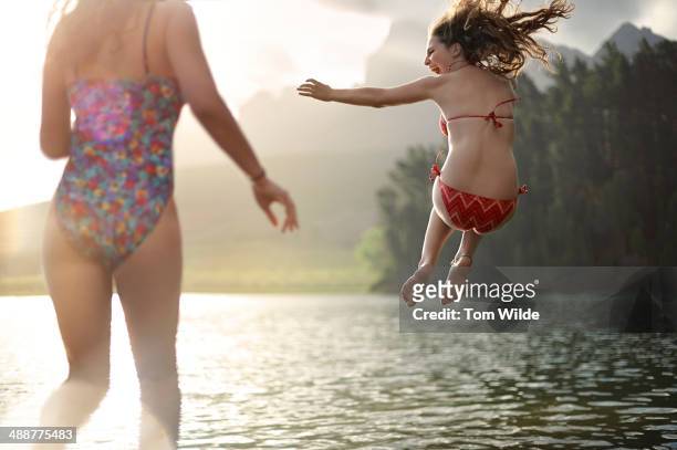 2 girls jumping into a lake - sprung ins wasser stock-fotos und bilder