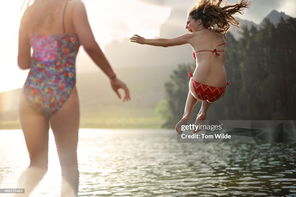 2 girls jumping into a lake
