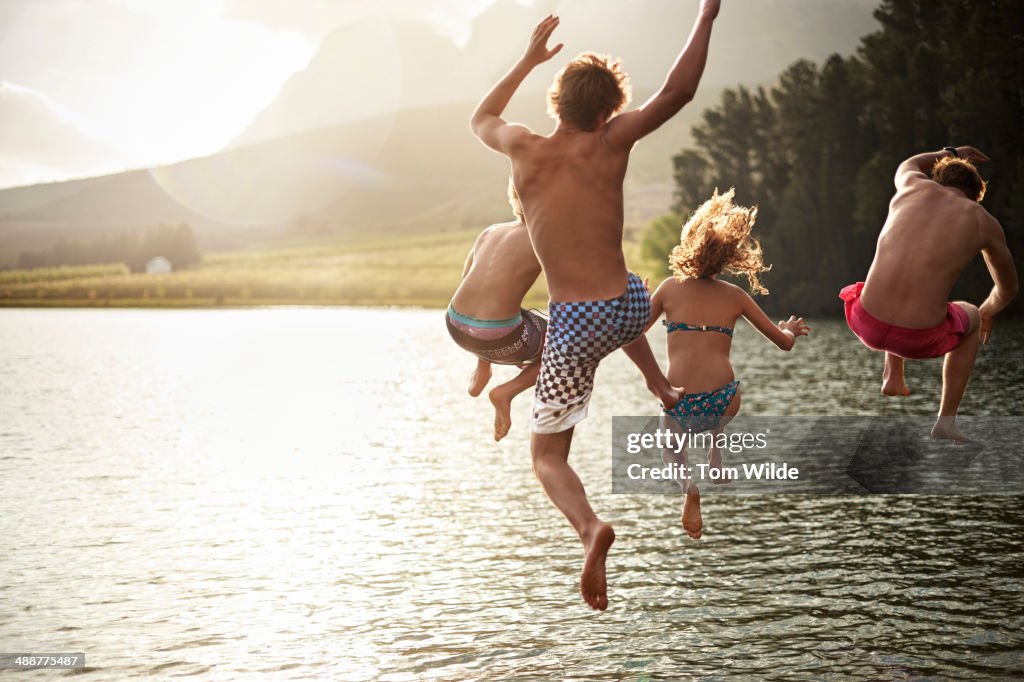 Four friends jumping into a lake in the mountains