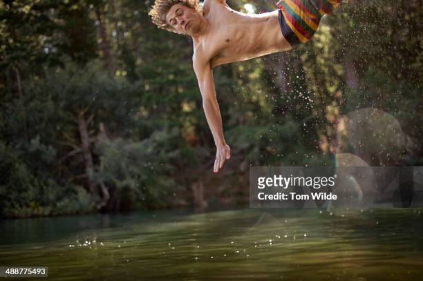 young man splashing into the water off a rope - altalena di corda foto e immagini stock