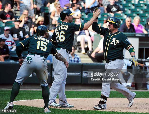 Billy Butler of the Oakland Athletics is greeted by Danny Valencia and Brett Lawrie after hitting a three-run home run against the Chicago White Sox...