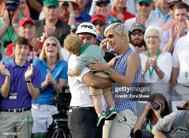 Bubba Watson of the United States celebrates with his wife Angie and their son Caleb on the 18th green after winning the 2014 Masters Tournament by a...