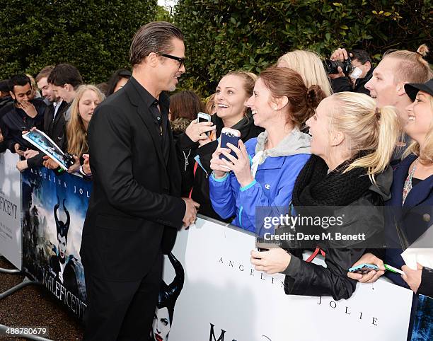 Brad Pitt signs autographs at a private reception as costumes and props from Disney's "Maleficent" are exhibited in support of Great Ormond Street...